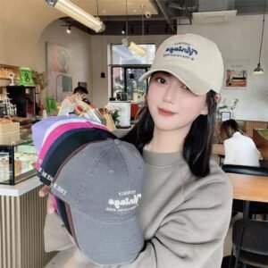 Cô gái đội nón lưỡi trai thêu Vintage màu kem và cầm nhiều mẫu nón Vintage khác trong quán cà phê phong cách Hàn Quốc